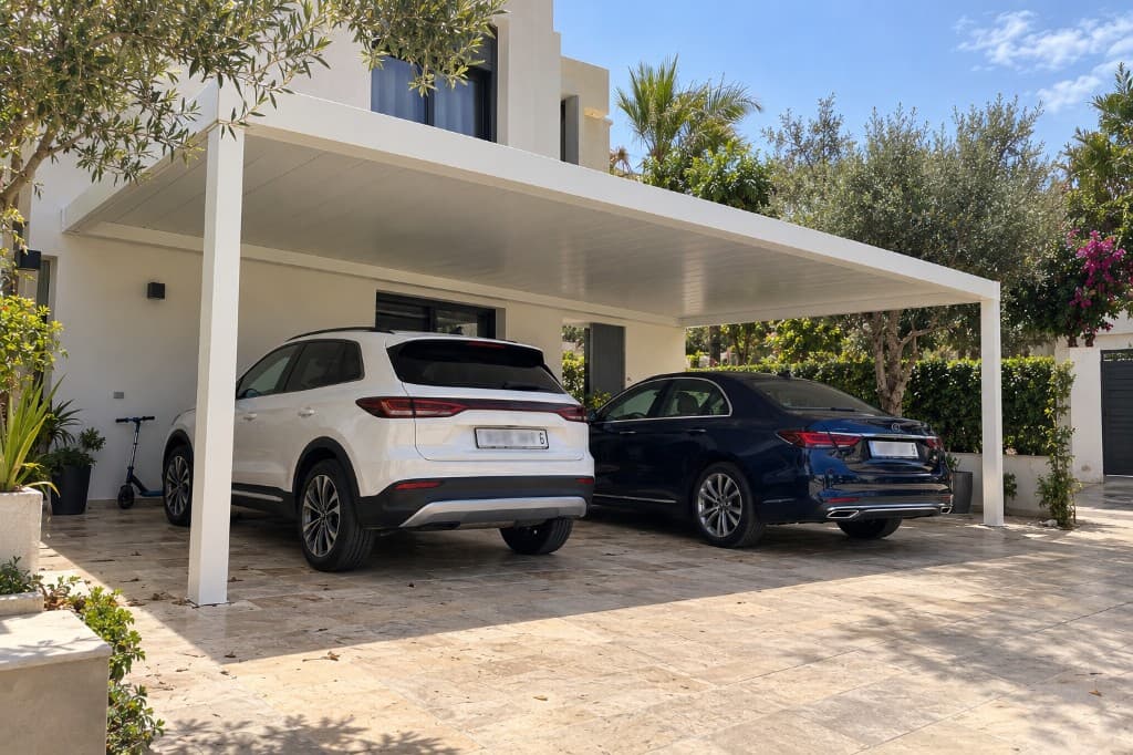 Carport aluminium blanc, deux véhicules côte à côte sous une toiture pleine.