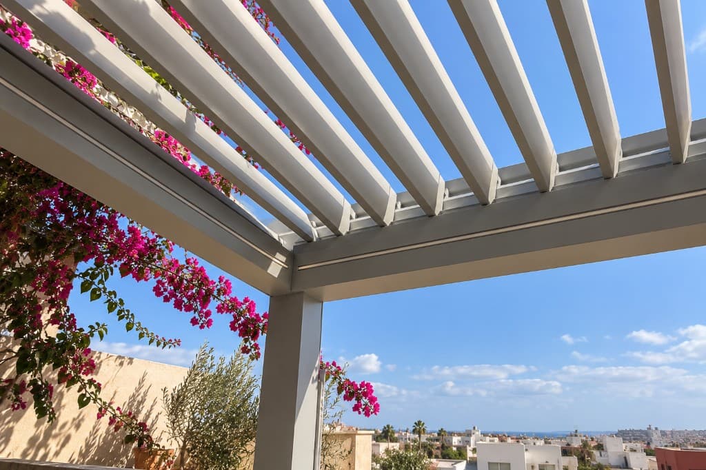 Lames d'une pergola vues de dessous, profil aluminium et ciel entre les lames.